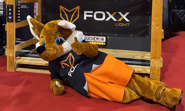 Mascotte Foxx Light devant sa bannière, print pensé avec Qreative