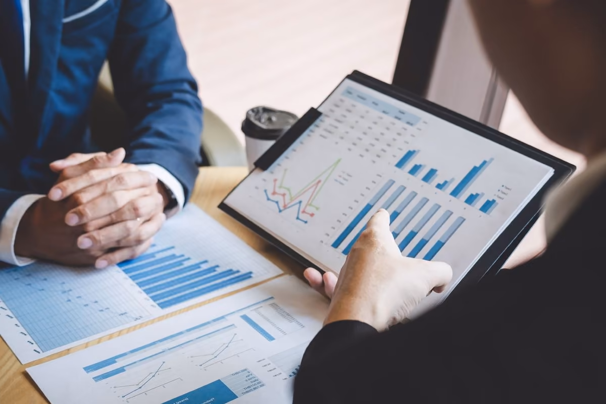 Two people analyse sales on a tablet, a topic covered by Qreative
