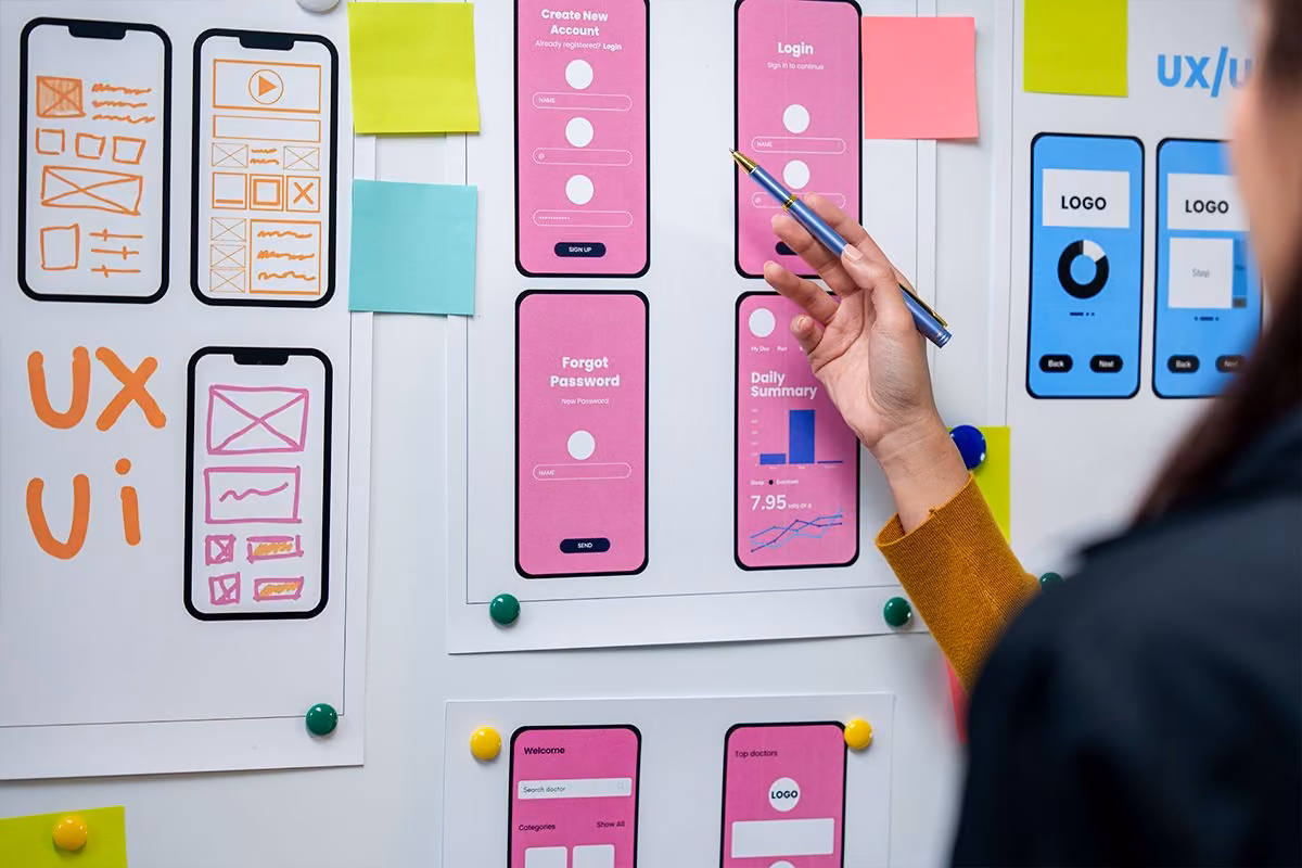 Main devant des maquettes mobile UI affichées chez Qreative