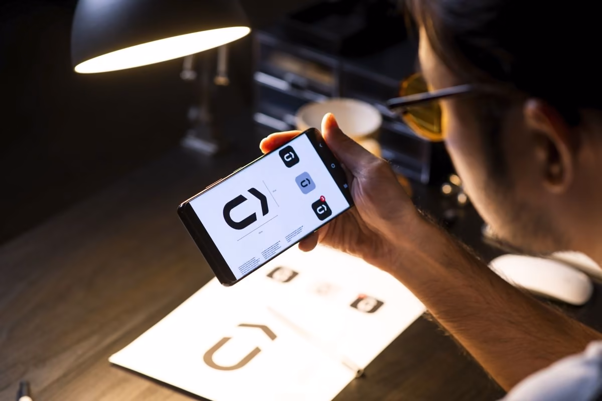 Designer testing a logo on a smartphone, as Qreative advises