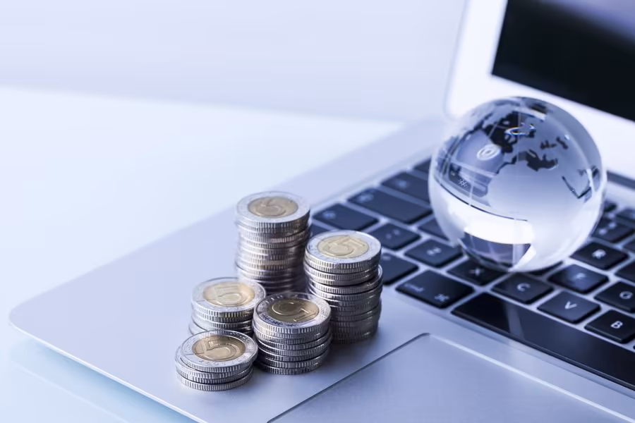 Capital numérique avec pièces et globe sur ordinateur chez Qreative