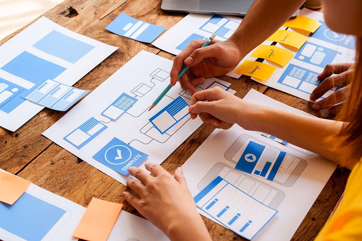 Hands drawing UX wireframes for a Qreative journey